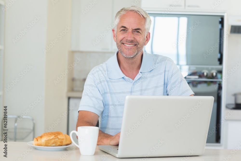 Happy man using his laptop at breakfast Happy man using his laptop at breakfast