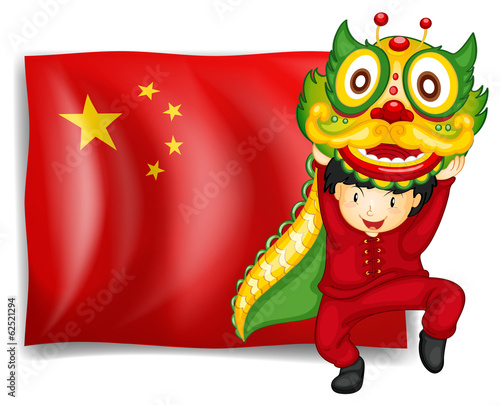 A boy doing the dragon dance in front of the flag of China