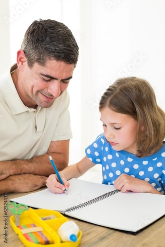 Girl drawing while father sitting by