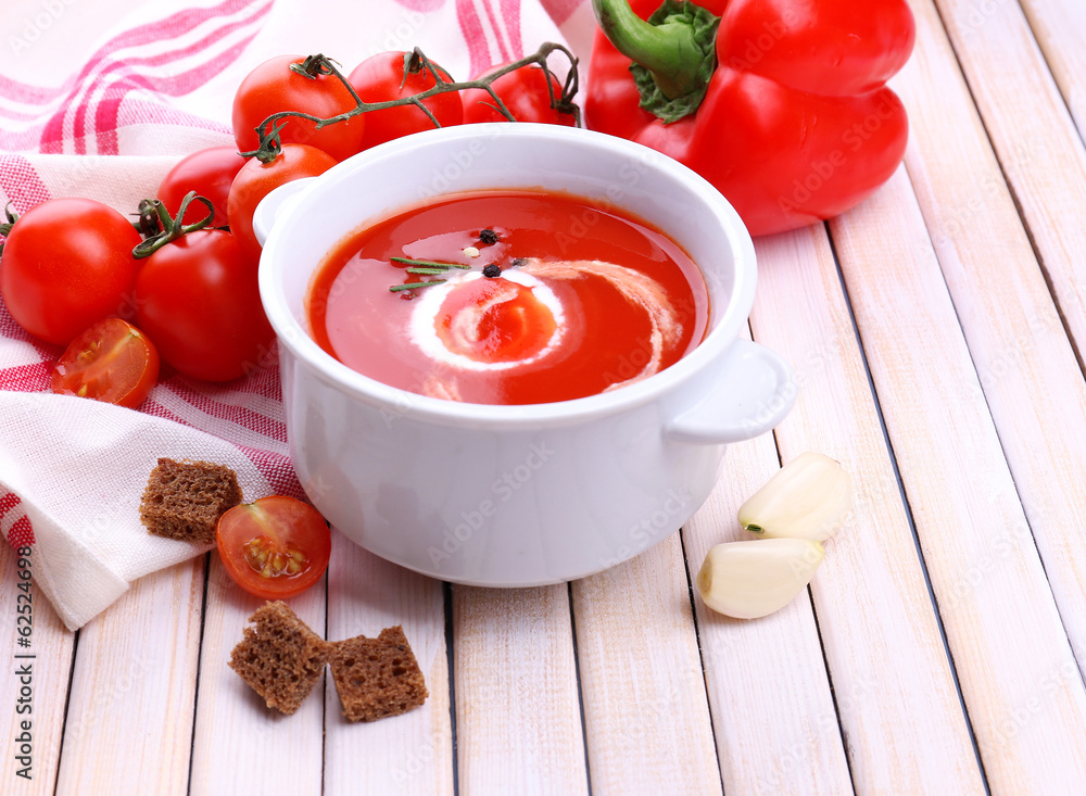 Tasty tomato soup and vegetables on wooden table Tasty tomato soup and vegetables on wooden table