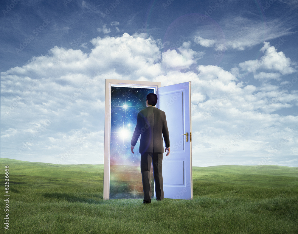 Fototapeta premium Businessman walking in open door to galaxy