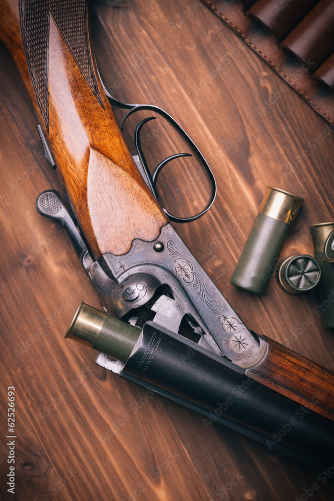 Shotgun with shells on wooden background Shotgun with shells on wooden background