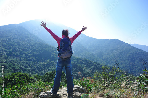 cheering hiking woman open arms at mountain peak