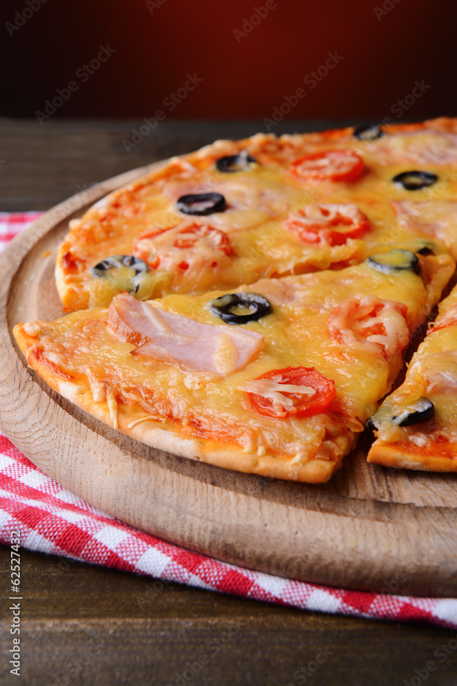Tasty pizza on table on dark red background Tasty pizza on table on dark red background