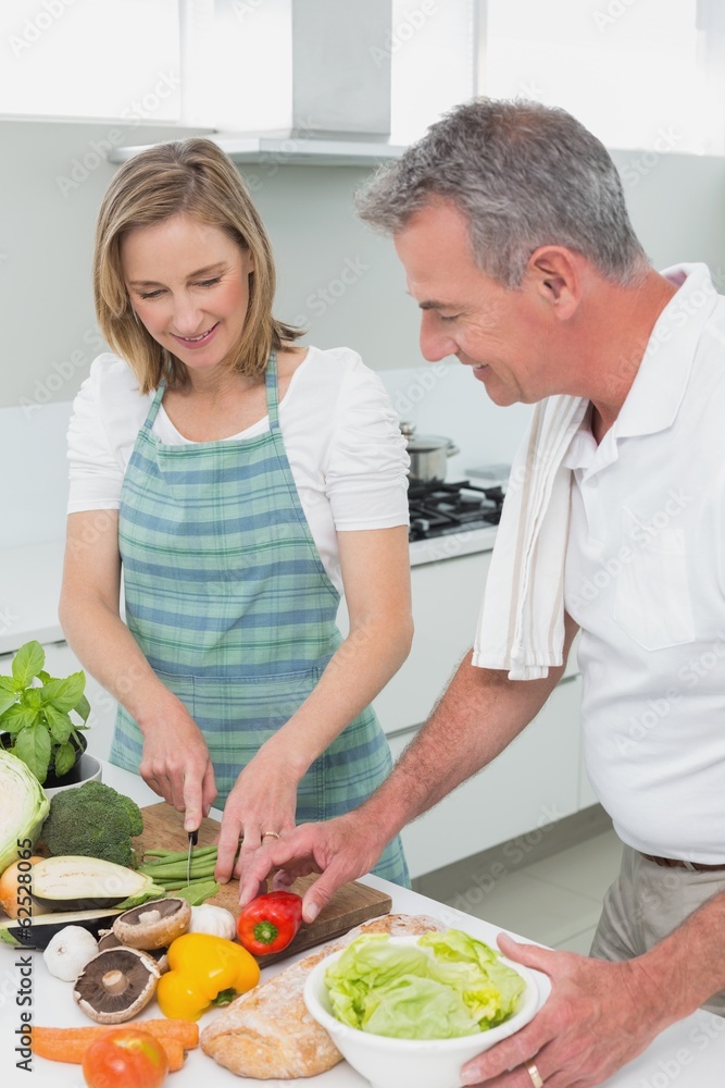 Happy couple preparing food together in kitchen Happy couple preparing food together in kitchen