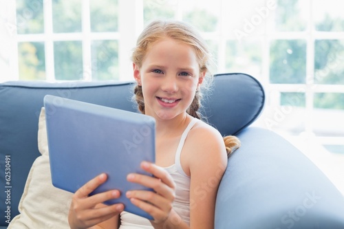 Young girl using digital tablet on sofa in living room