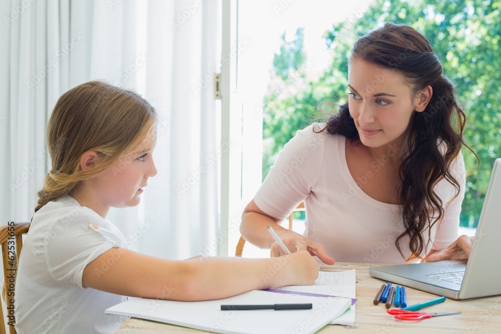 Woman with laptop assisting daughter in homework Woman with laptop assisting daughter in homework