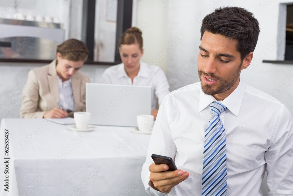 Fototapeta premium Businessman text messaging with colleagues at office desk