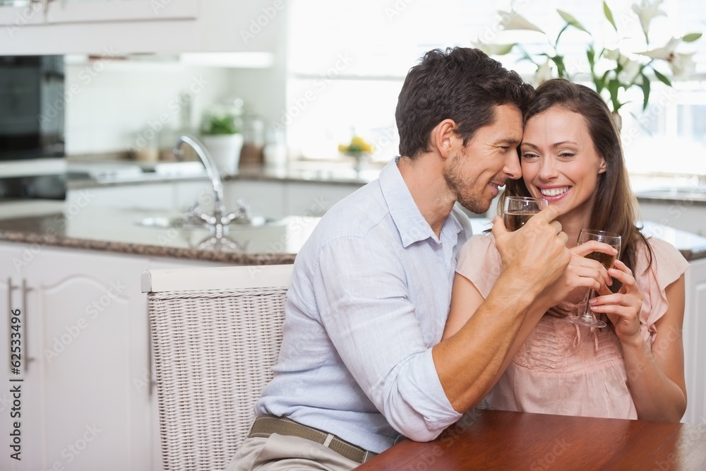 Couple with wine glasses sitting in kitchen Couple with wine glasses sitting in kitchen