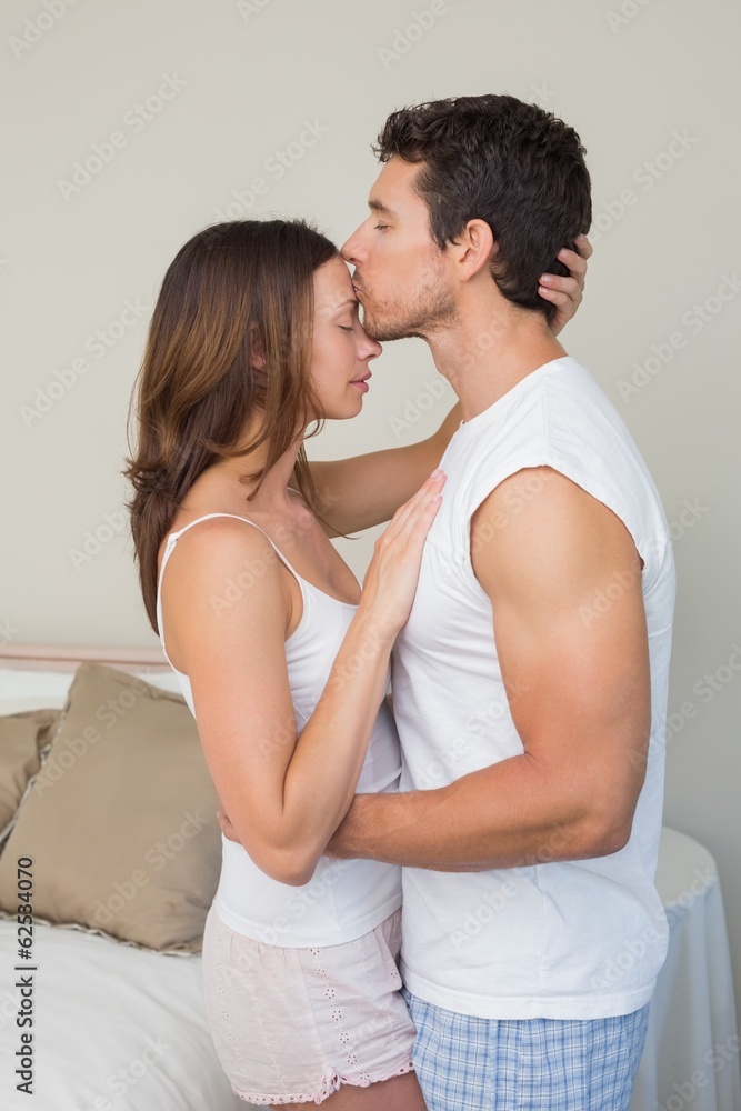 Loving man kissing womans forehead at home Loving man kissing womans forehead at home