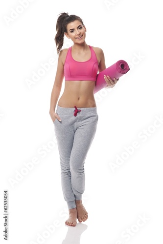 Young woman carrying yoga mat © gpointstudio