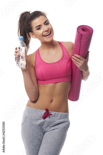 Healthy woman holding bottle of mineral water and exercise mat © gpointstudio