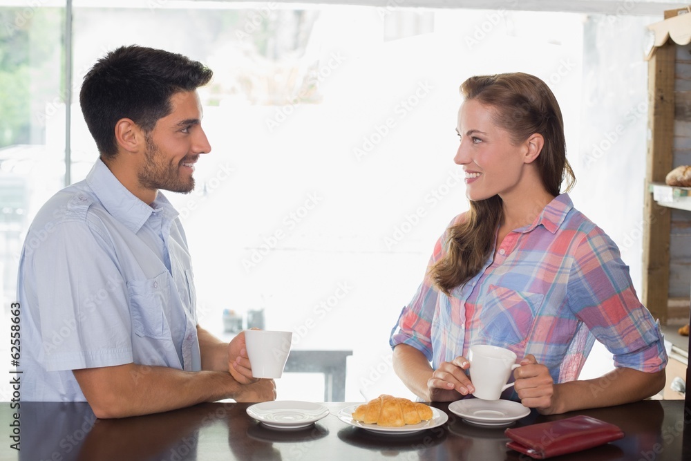 Smiling couple with coffee and croissant at coffee shop Smiling couple with coffee and croissant at coffee shop