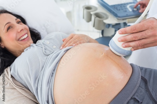 Smiling pregnant woman receiving ultrasound