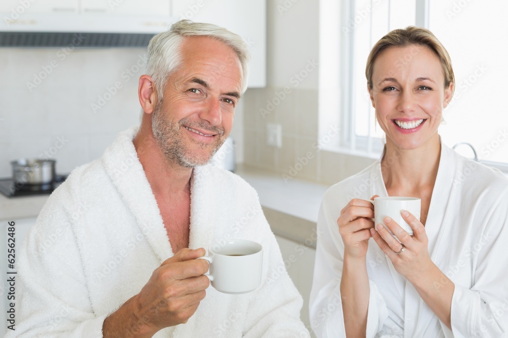 Smiling couple having coffee at breakfast in bathrobes