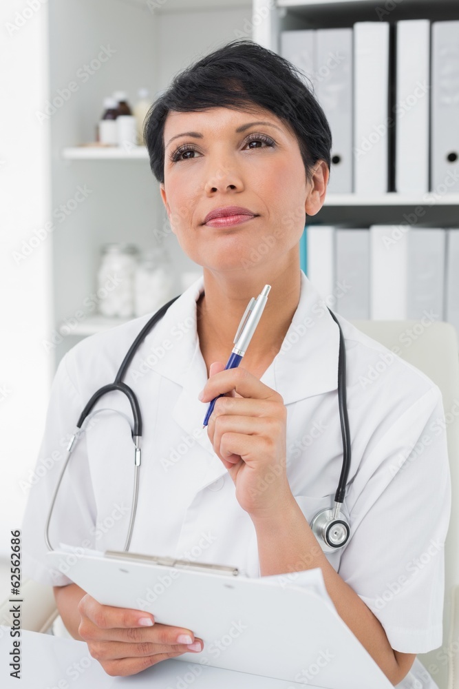 Thoughtful female doctor writing on clipboard Thoughtful female doctor writing on clipboard