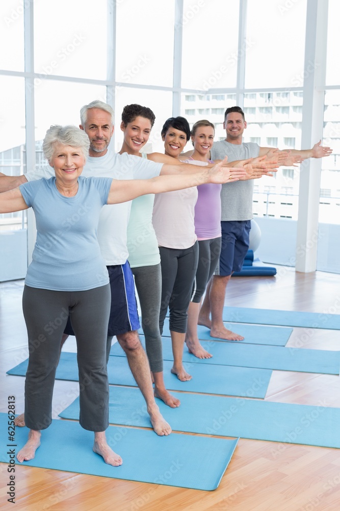 Fototapeta premium Class stretching hands in row at yoga class