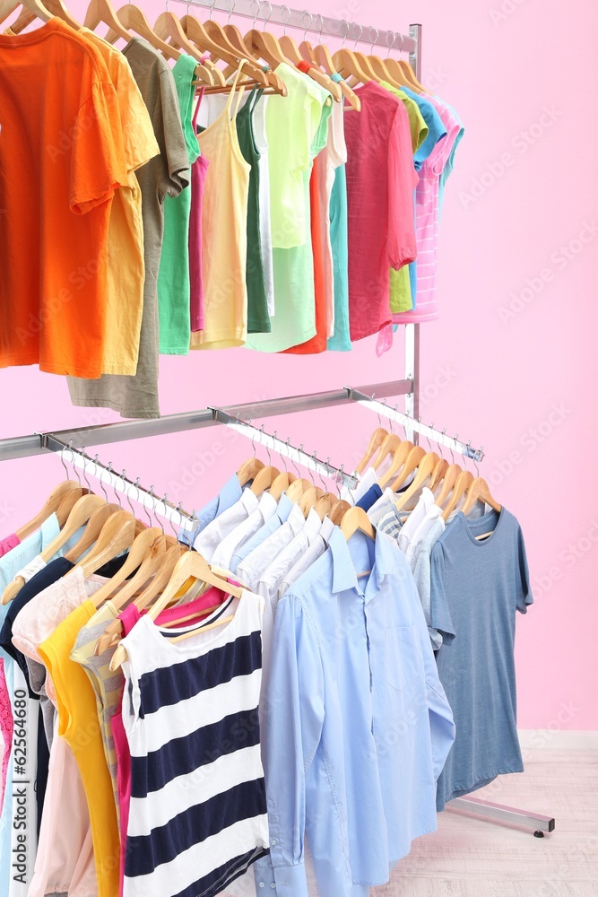 Obraz premium Different clothes on hangers, on pink background
