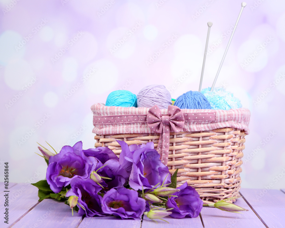 Purple artificial eustoma and woolen balls of yarn in basket Purple artificial eustoma and woolen balls of yarn in basket