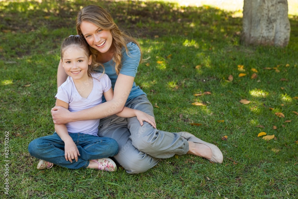 Fototapeta premium Smiling mother embracing her daughter at park