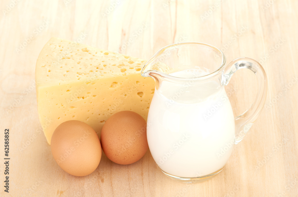 Big piece of cheese, glass jug with milk Big piece of cheese, glass jug with milk