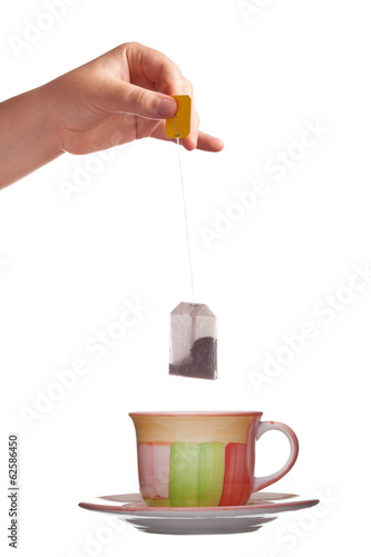 tea bag in hand and cup isolated on white background