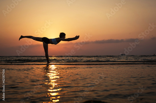 Yoga silhouette on the beach, virabhadrasana pose.Feb 25, 2014