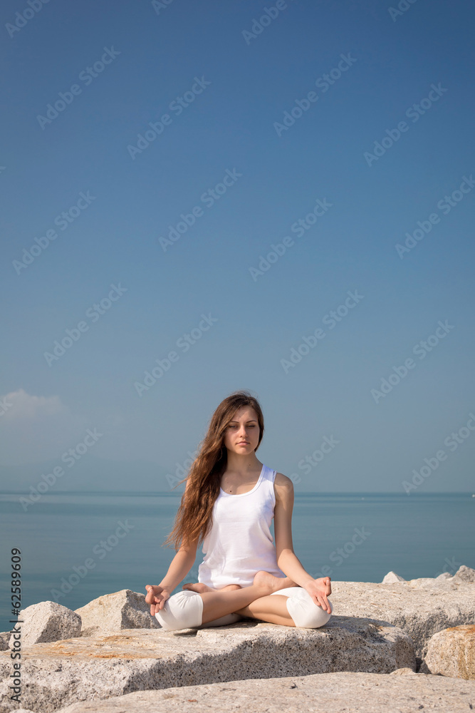 Beautiful woman in Lotus posture on the beach