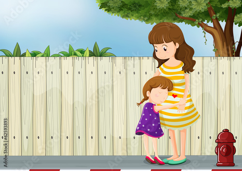 A mother and her daughter near the fence at the road