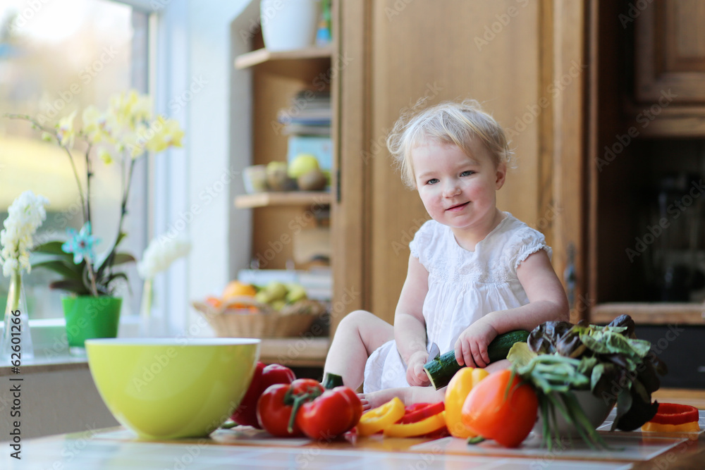 Toddler girl cutting cucumber preparing healthy vegetables salad Toddler girl cutting cucumber preparing healthy vegetables salad