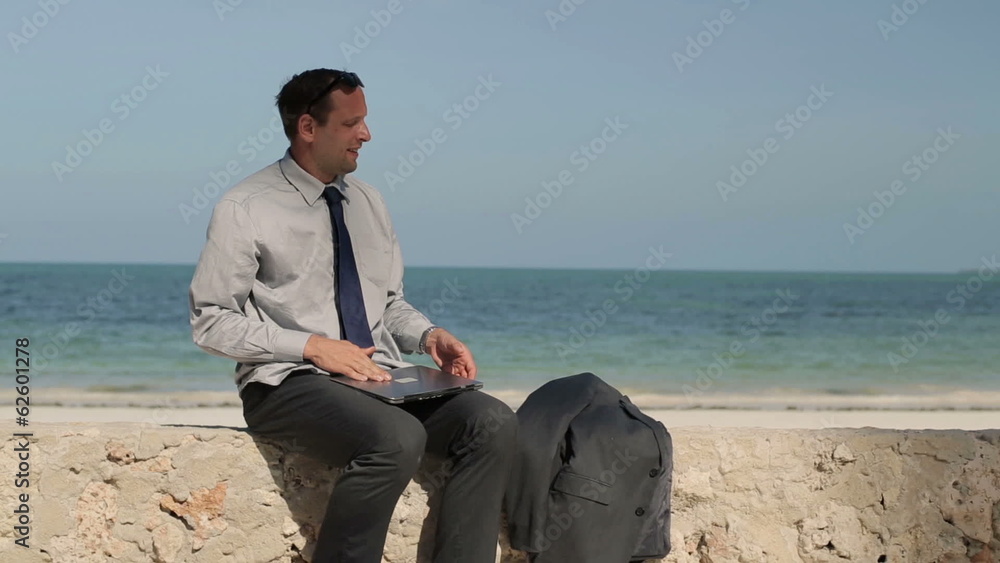 Businessman finishing work on laptop and relaxing by the sea