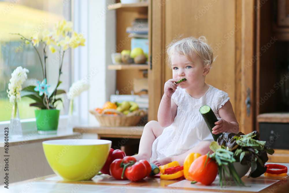 Adorable girl eating cucumber preparing healthy vegetables salad Adorable girl eating cucumber preparing healthy vegetables salad