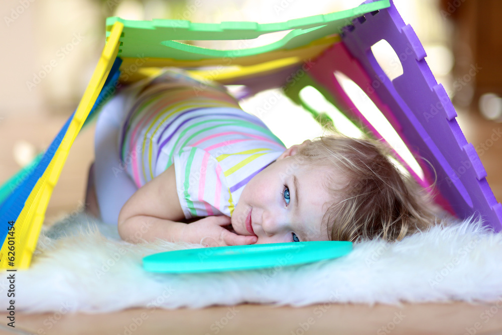 Happy little toddler girl playing hide and seek with puzzles Happy little toddler girl playing hide and seek with puzzles