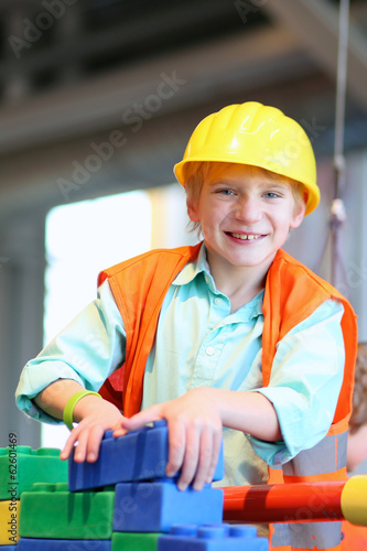 Happy boy in safety helmet playing indoors building house
