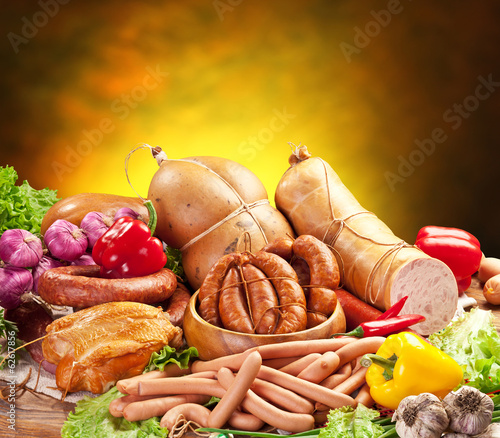 Still-life with sausage products, vegetables and herbs.