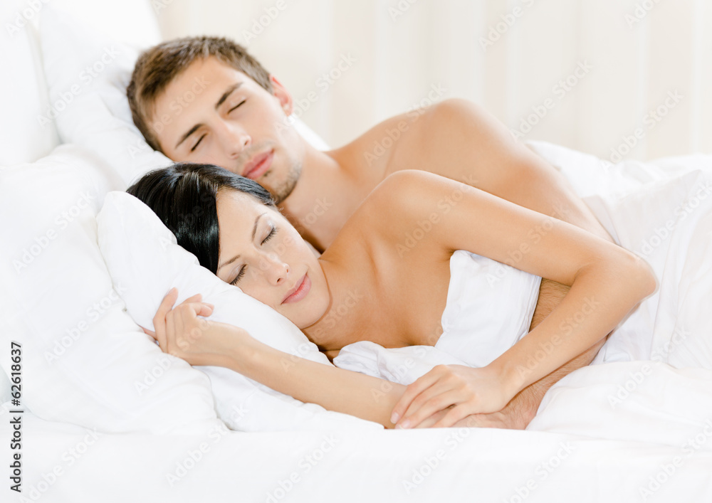 Obraz premium Couple sleeping in bed under white eiderdown