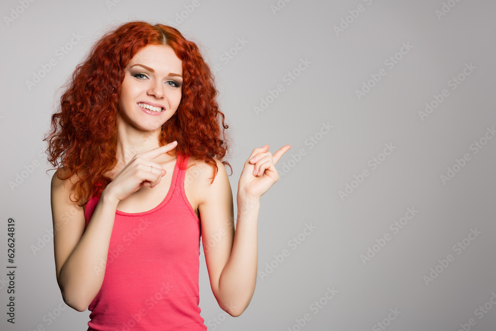 Smiling red haired girl is pointing fingers Smiling red haired girl is pointing fingers