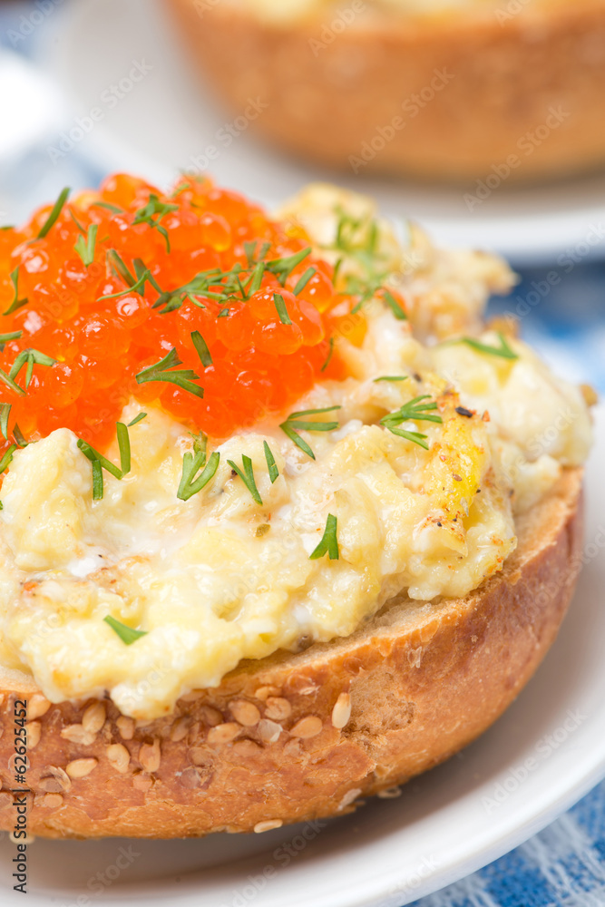 scramble eggs with red caviar on a wheat bun, close-up scramble eggs with red caviar on a wheat bun, close-up