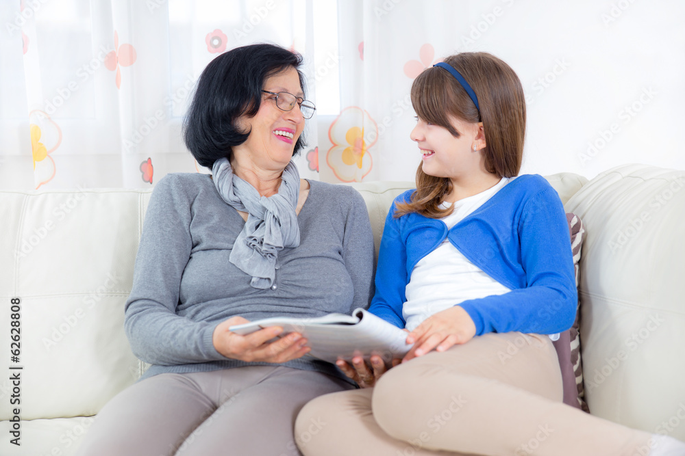 Grandmother and little girl reading magazine together at home Grandmother and little girl reading magazine together at home