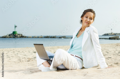 Businesswoman with laptop sitting on a beach