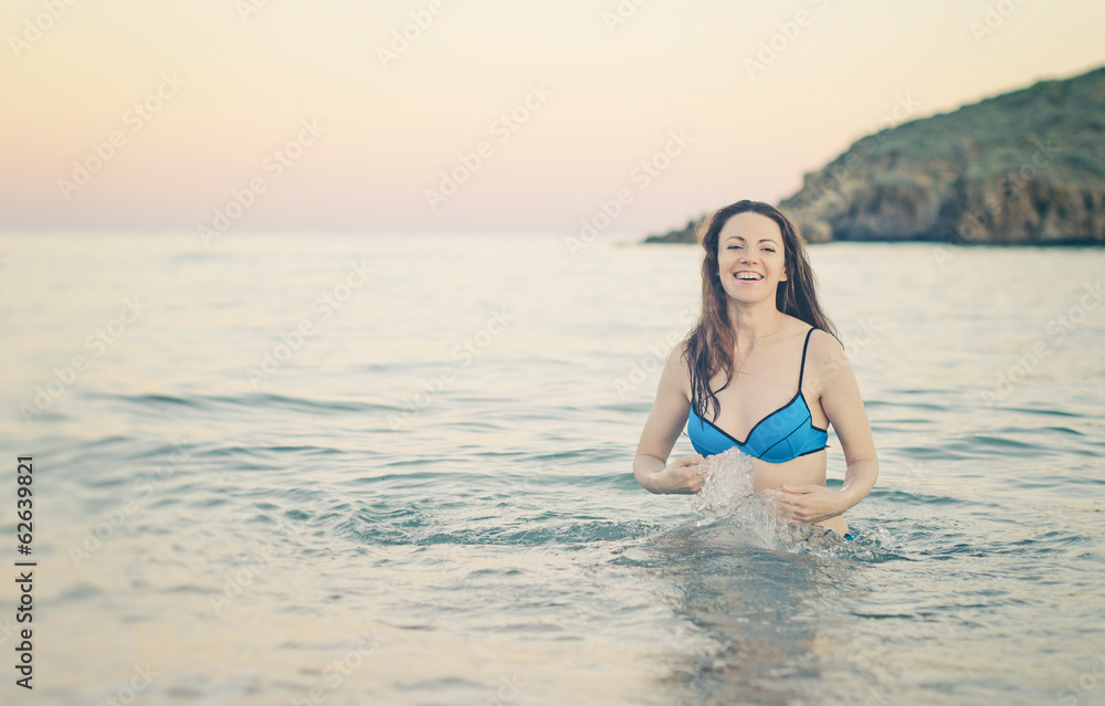 Happy woman in the sea splashing water. Vintage effect.