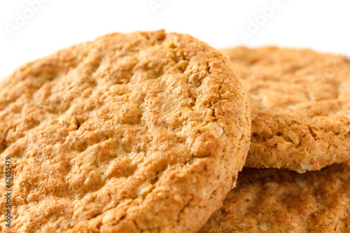 Detail of three crispy golden oat biscuits on white