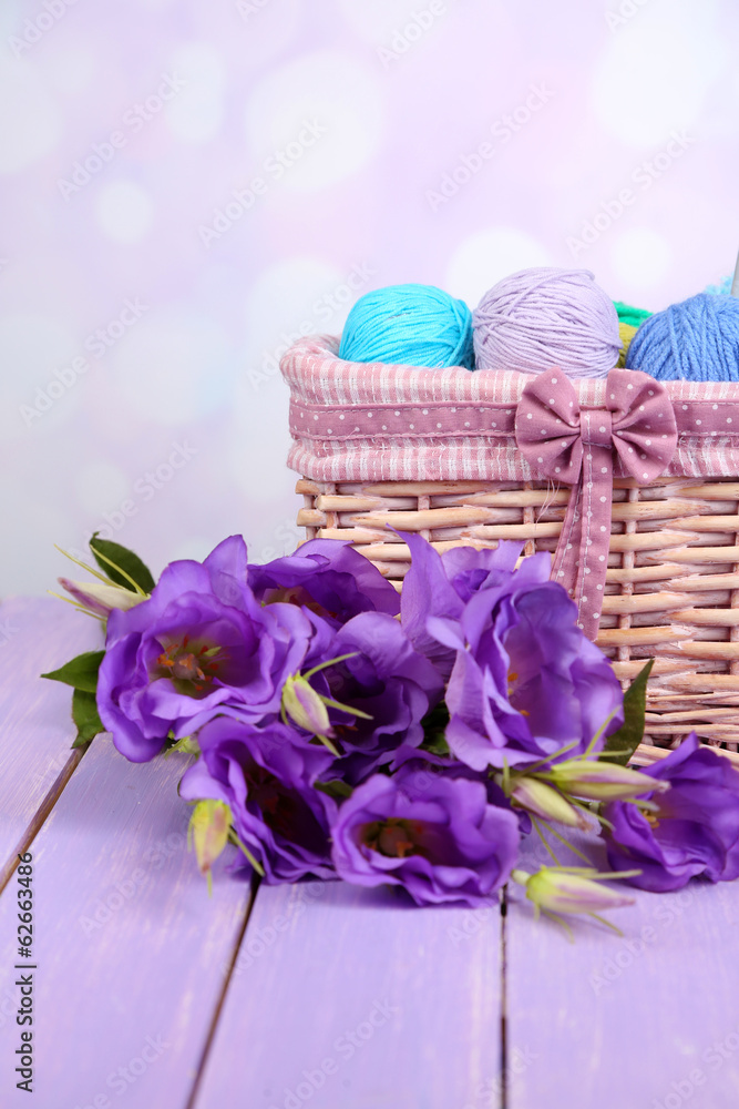 Purple artificial eustoma and woolen balls of yarn in basket