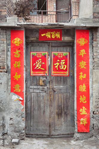 Old wooden Chinese door with peeling fortune posters