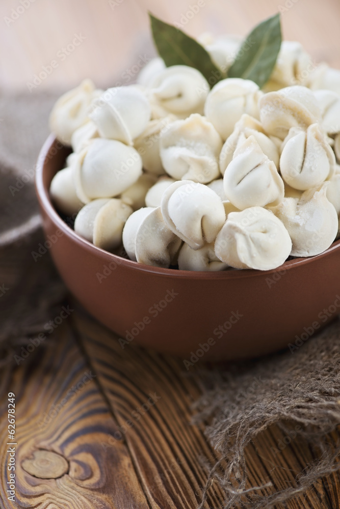 Close-up of raw pelmeni in a glass bowl, vertical shot Close-up of raw pelmeni in a glass bowl, vertical shot