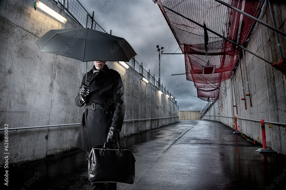 Businessman holding black umbrella on rainy day