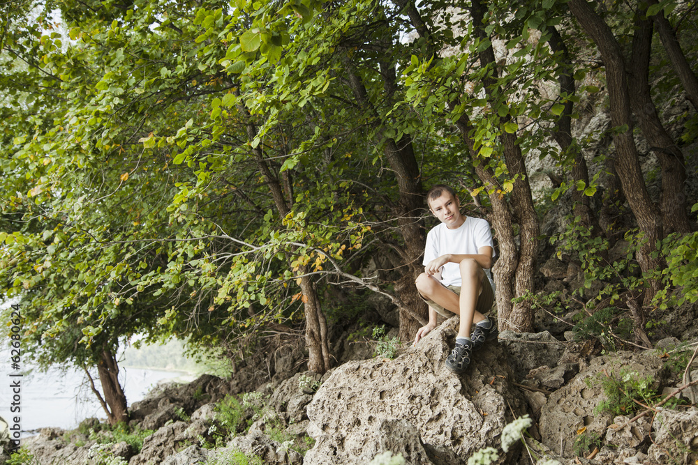 the boy sits on a stone the boy sits on a stone