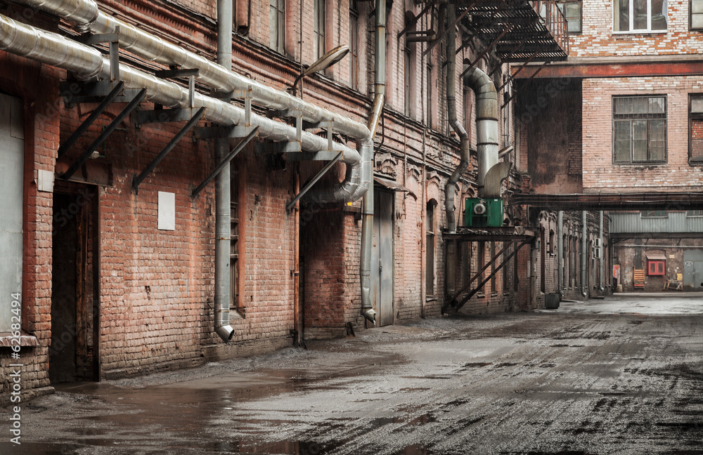 Old industrial street view with red brick facades and tubes