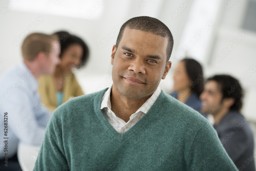 Business Meeting. A Group Sitting Down Around A Table. A Man Smiling Confidently. Business Meeting. A Group Sitting Down Around A Table. A Man Smiling Confidently.