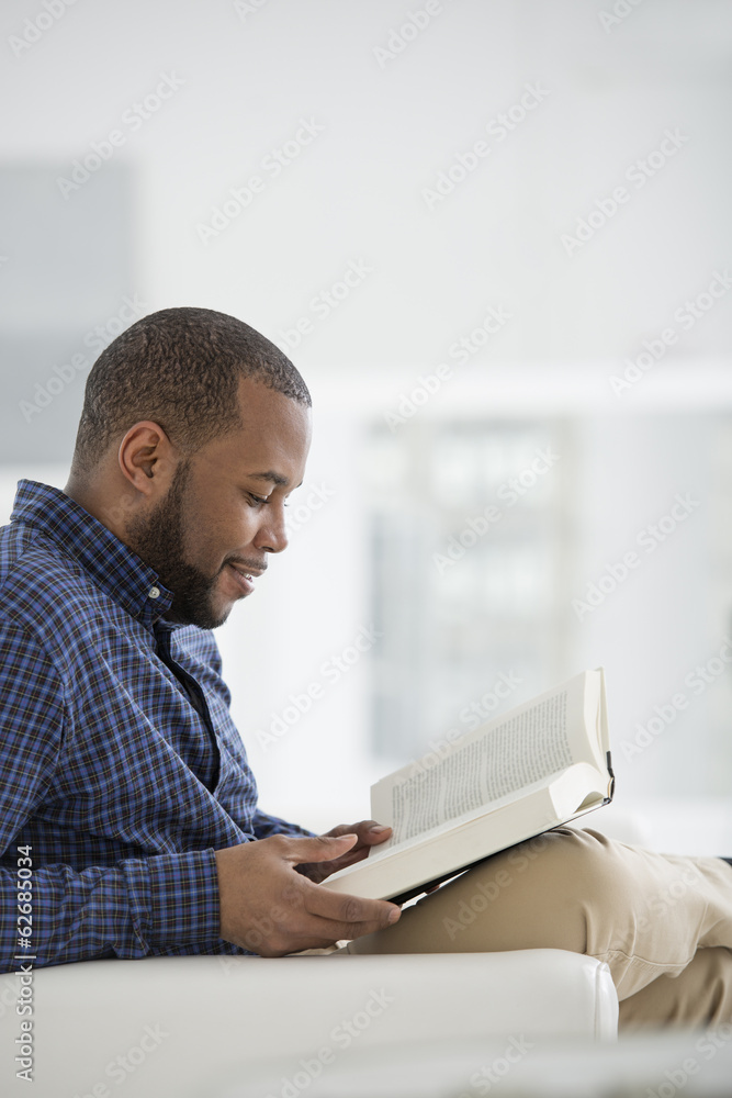 A Bright White Room Interior. A Man Sitting Reading A Book. A Bright White Room Interior. A Man Sitting Reading A Book.